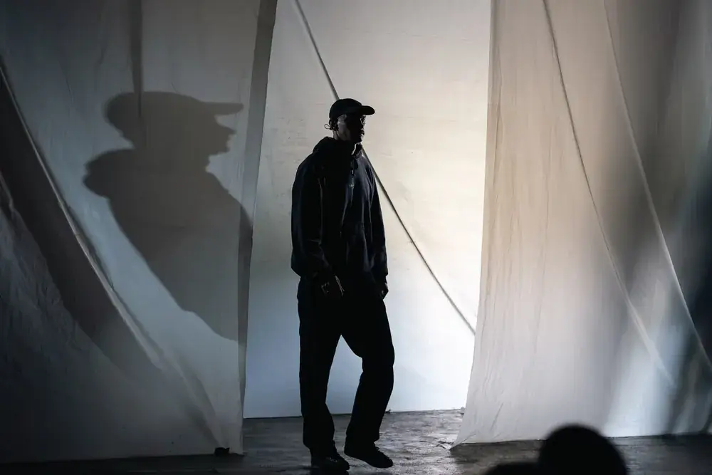 Crew member walking past white drapes in silhouette