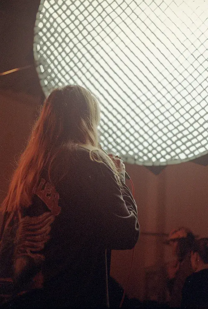 Sonya Shats singing under a gridded soft light, behind the scenes of Po Fanku