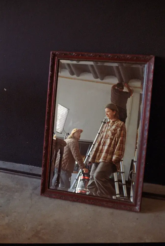 Crew rigging the set, seen in a mirror on the floor