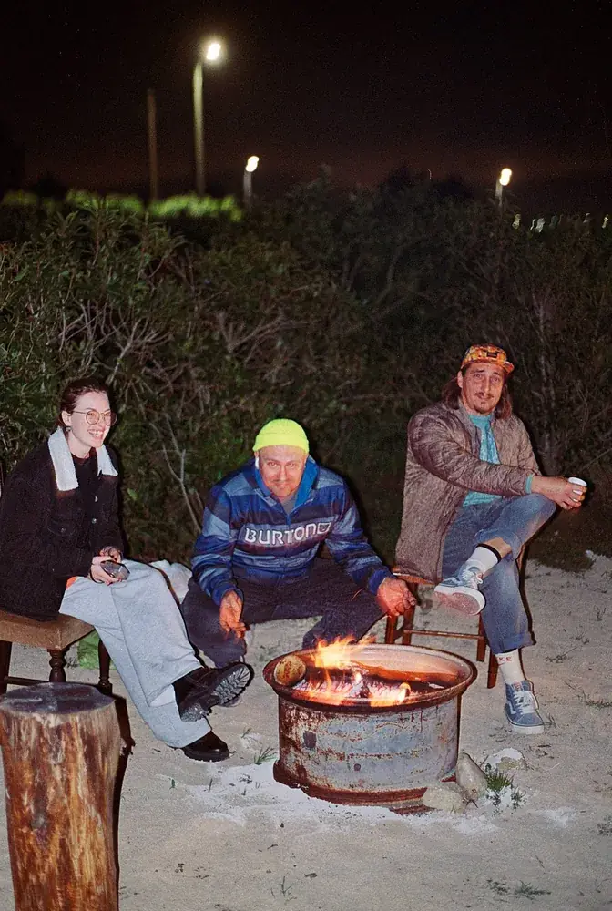 Crew around a fire pit at night after the shoot