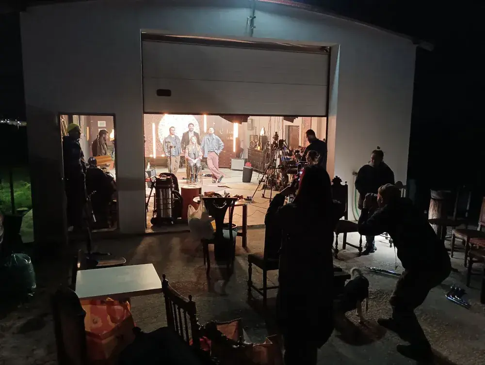 Live session set lit inside a barn at night, crew filming from outside, Lisbon Sessions