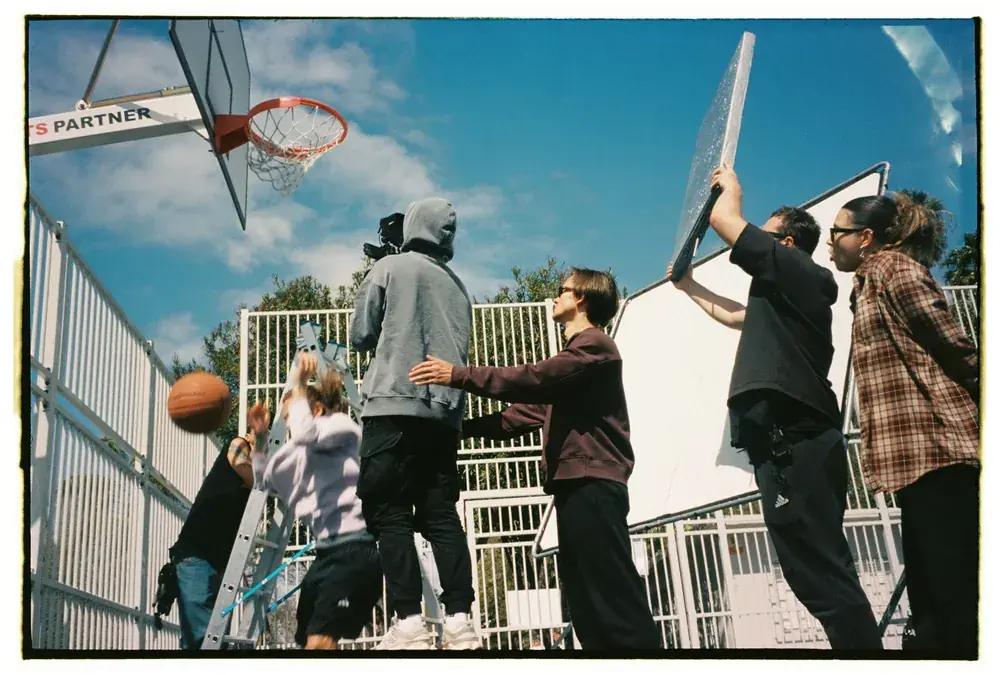 Comuna Production crew with camera and reflector filming on a basketball court