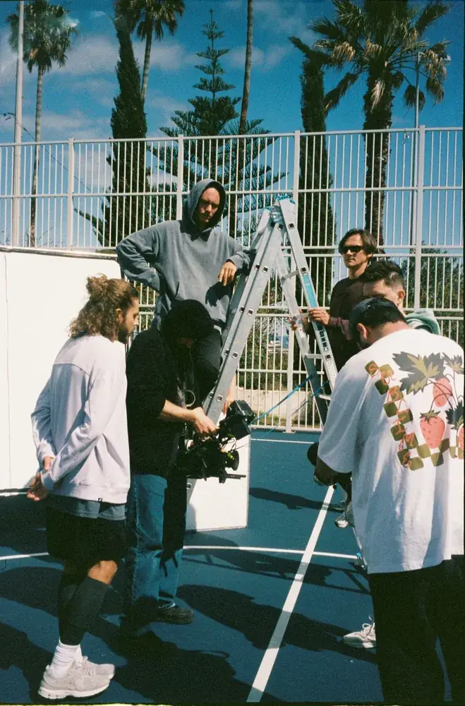 Camera crew and a ladder on an outdoor basketball court shoot in Lisbon, film photo