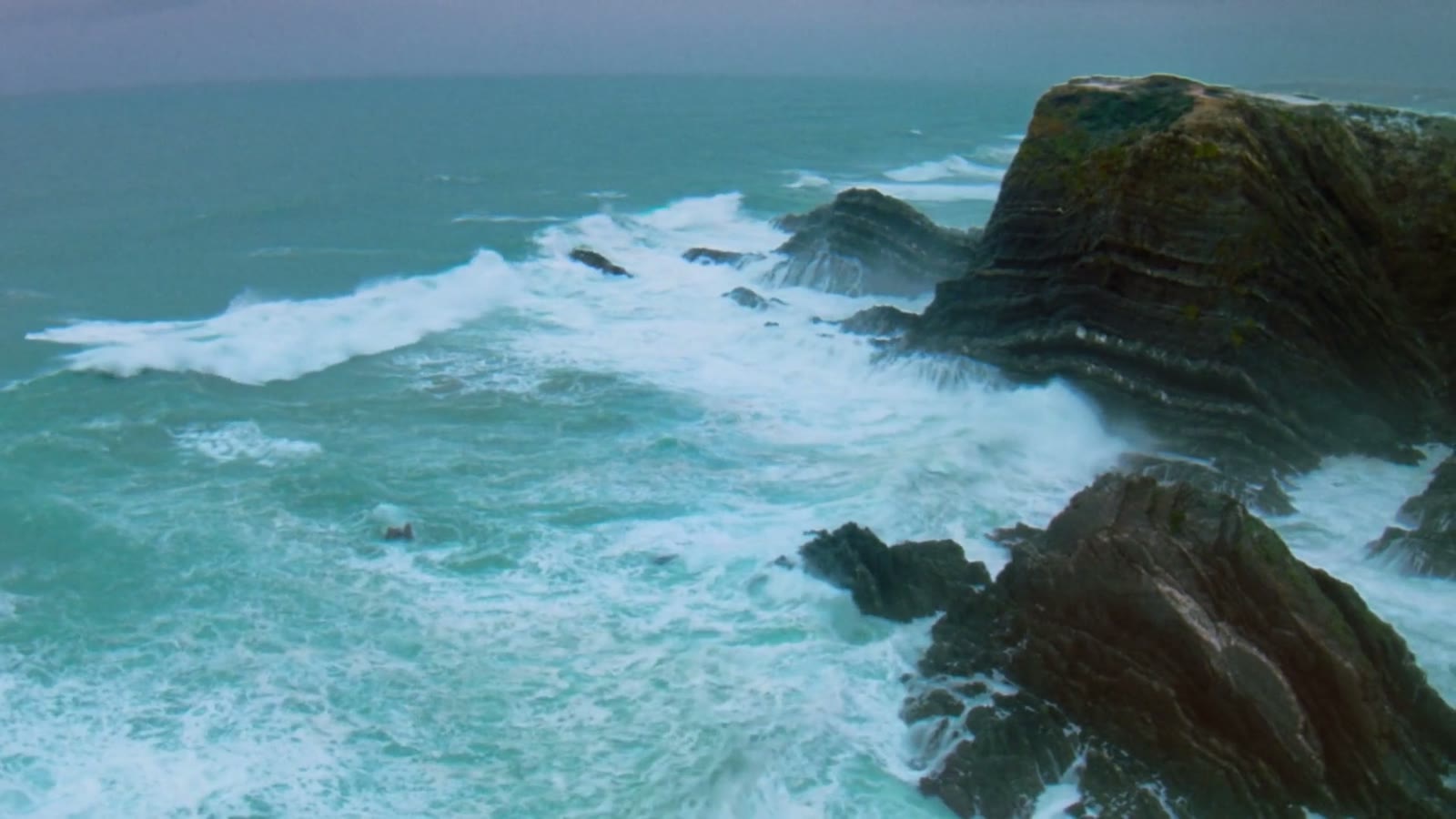 Waves breaking on rocks on the Portuguese coast, opening shot of the Comuna Production showreel
