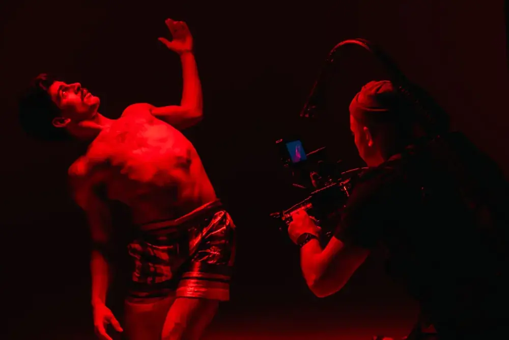 Dancer performing under red light while the crew films