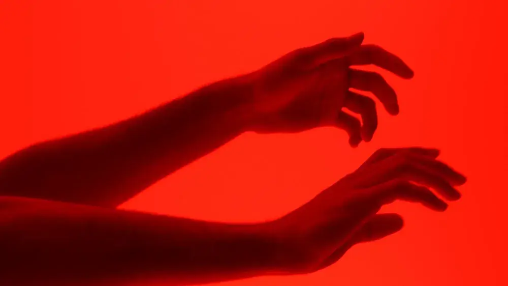 Silhouette of red-painted hands, still from Transformation