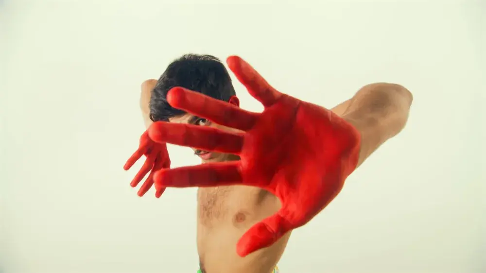 Red-painted hand reaching towards the camera